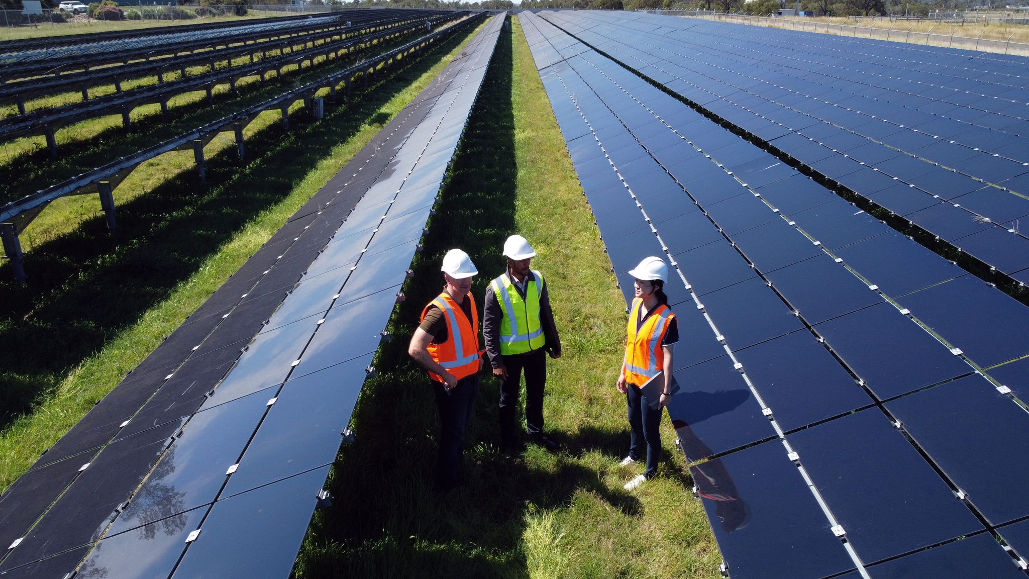 Solar panels in a field with three workers