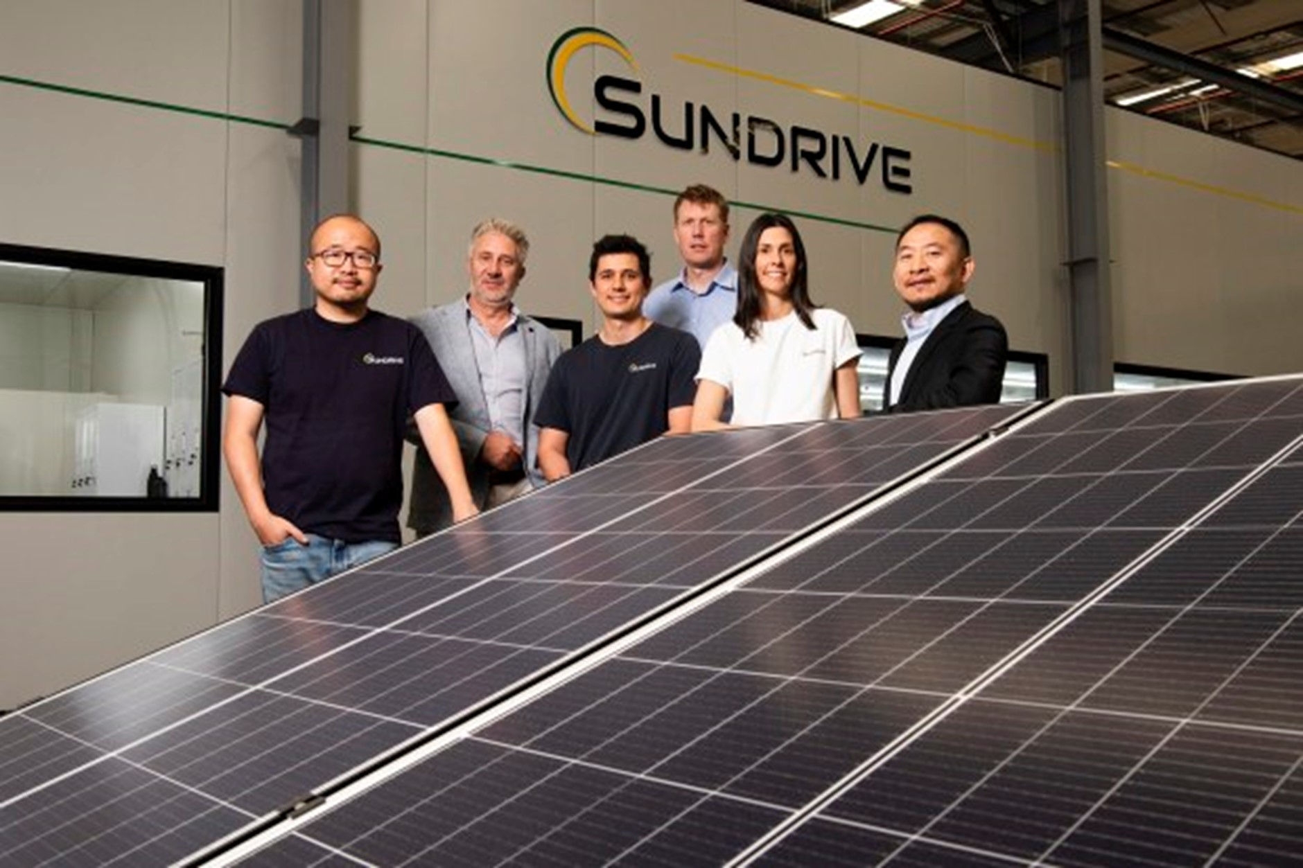 people standing next to a large solar panel in a factory