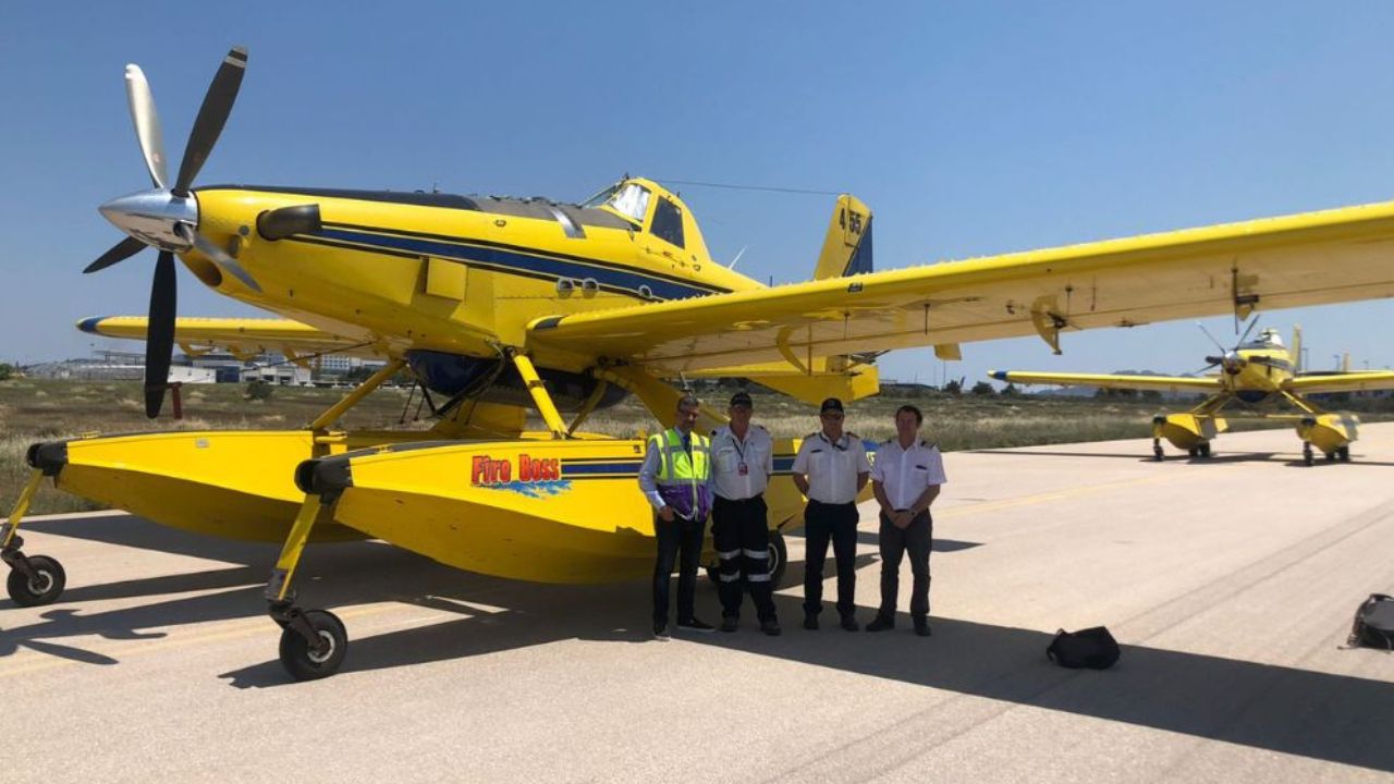 Four men stand alongside a yellow floatplane firefighting aircraft in Greece