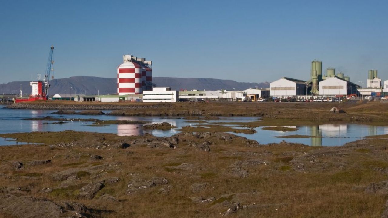 Three red and white striped smelter towers stand in the centre of an aluminium smelter in Iceland