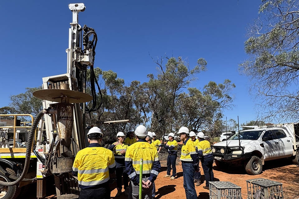 Group of workers surrounding a large drill