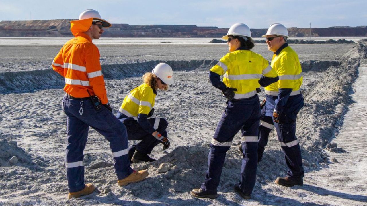 Four mine technicians standing in a group with high visibility vests
