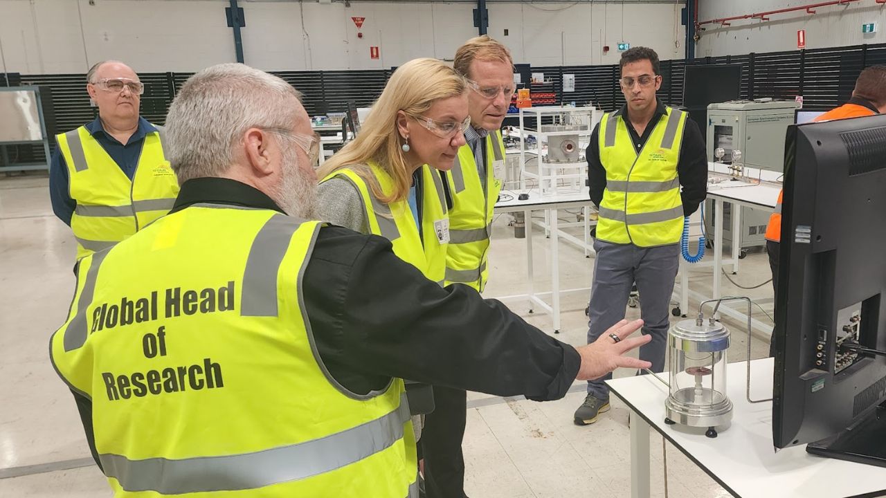A group of 5 people in high-visibility vests. A man is providing a demonstration to the woman in the centre of the group (EU Energy Commissioner Kadri Simson).