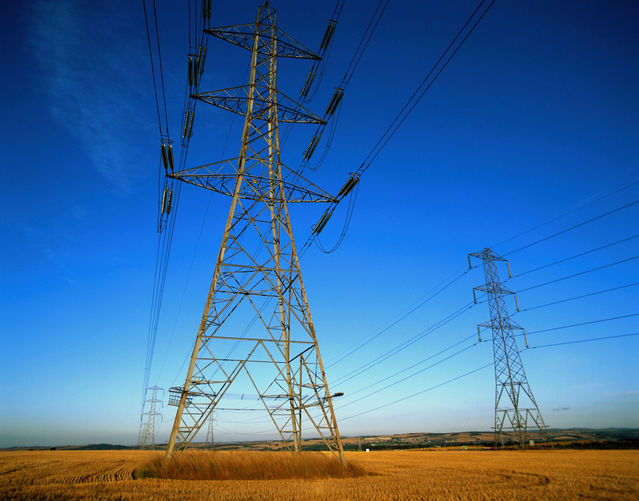 Tall, steel structure carries high voltage power lines across a field.