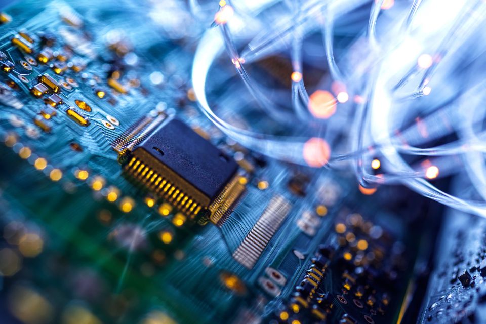A close up of fibre optics carrying data passing through electronic circuit boards