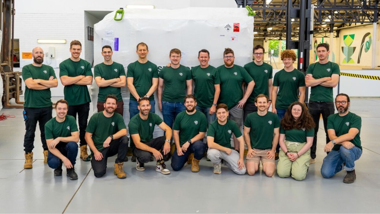 A group of men and women wearing green t-shirts pose for a group photo