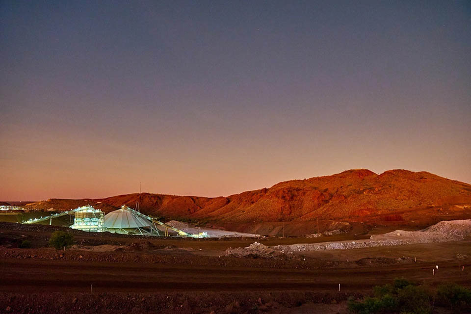 Illuminated mine at early light with red hills in the background